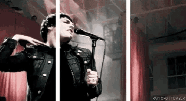 a man in a black jacket is singing into a microphone on stage .