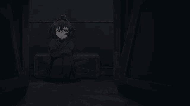 a girl is sitting in a dark room with her legs crossed