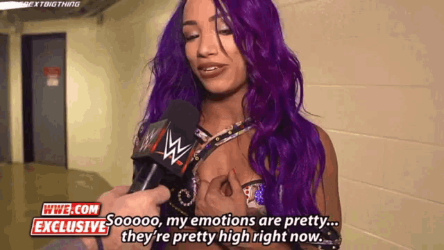 a woman with purple hair is talking into a microphone with wwe.com exclusive written in the corner