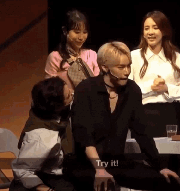 a group of people are sitting on a stage and one of them has a sign that says try it