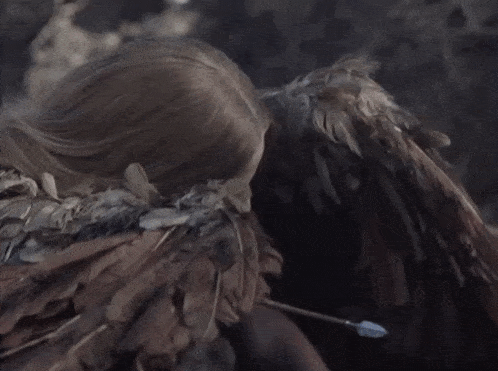 a close up of a woman with feathers on her wings