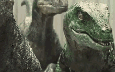 a group of dinosaurs are standing next to each other looking at the camera .