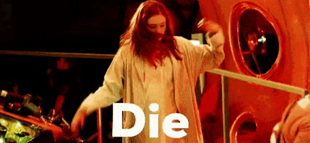 a woman with red hair is standing in front of a wall with the word die on it