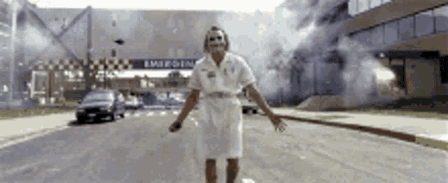 a man in a white nurse 's uniform is standing in front of an emergency room .