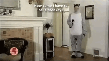 a man in a donkey costume is standing in a living room next to a dog .