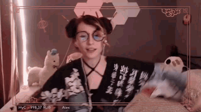 a woman wearing glasses and a sweater with chinese writing on it is sitting on a bed .
