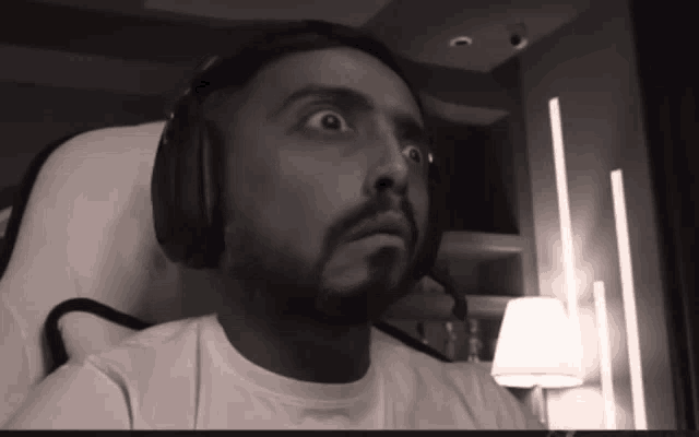 a man wearing headphones and a white shirt is sitting in a chair
