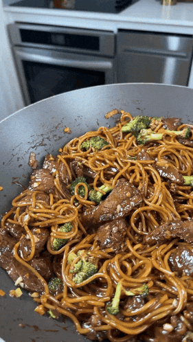 a wok filled with noodles broccoli and meat