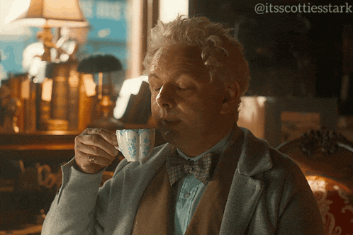 a man in a bow tie is drinking a cup of coffee