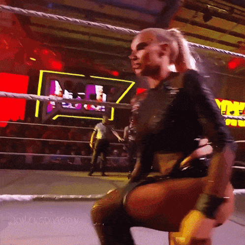 a woman is kneeling down in a wrestling ring with the word division on the bottom right corner