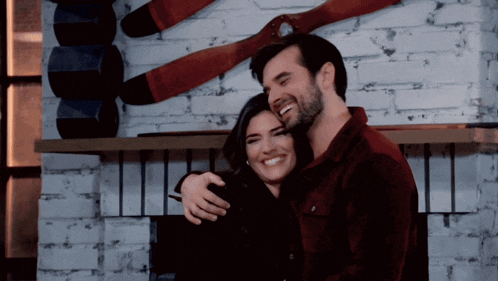 a man and a woman are hugging each other in front of a fireplace
