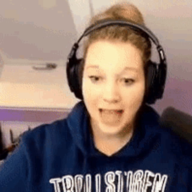 a young woman wearing headphones and a blue hoodie is talking .