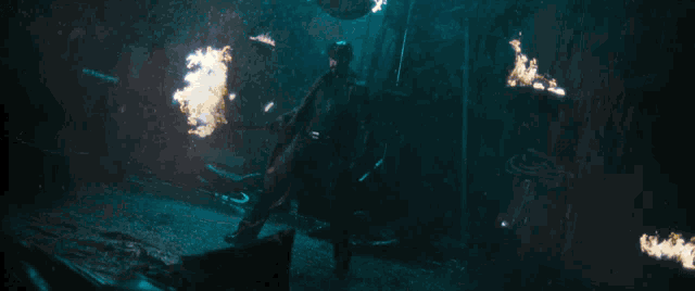 a man in a cowboy hat is standing in a dark room with fire coming out of his hands