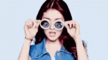 a woman wearing sunglasses and a denim jacket is making a face .