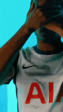 a man wearing a white nike shirt with the letter a on it covering his face .