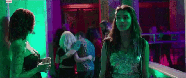 two women are standing next to each other in a dark room with purple lights .