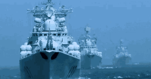 a row of military ships are floating in the ocean