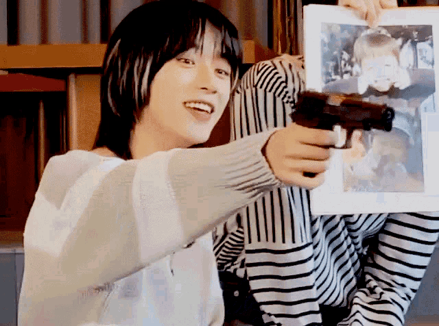 a woman in a striped shirt is holding a gun and a picture of a baby
