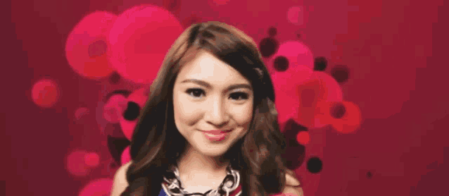 a woman with a necklace is smiling in front of a red background