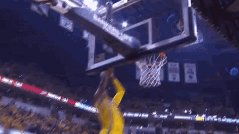 a basketball player is dunking a ball in front of a bankers life sign .