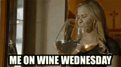 a woman is drinking from a large glass of wine .