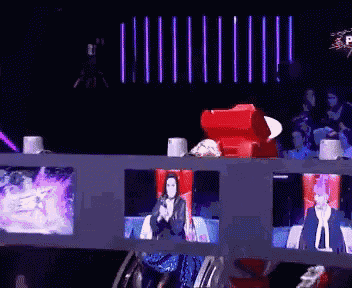 a woman is sitting in a red chair behind a fence watching a show