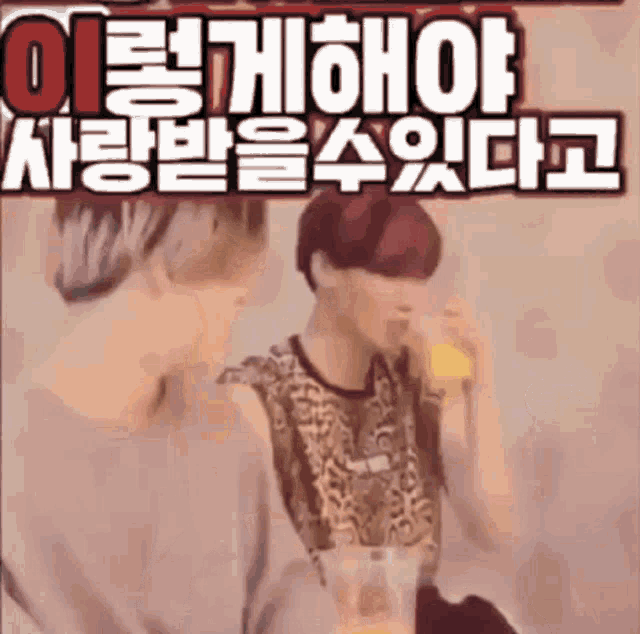 a man with red hair is drinking a drink from a cup while another man looks on .