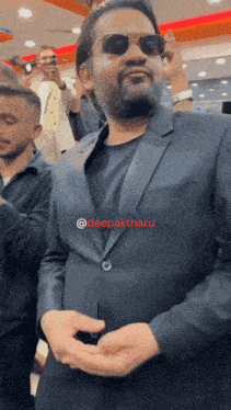 a man in a suit and sunglasses is standing in a crowd with the name deepakthau on the bottom