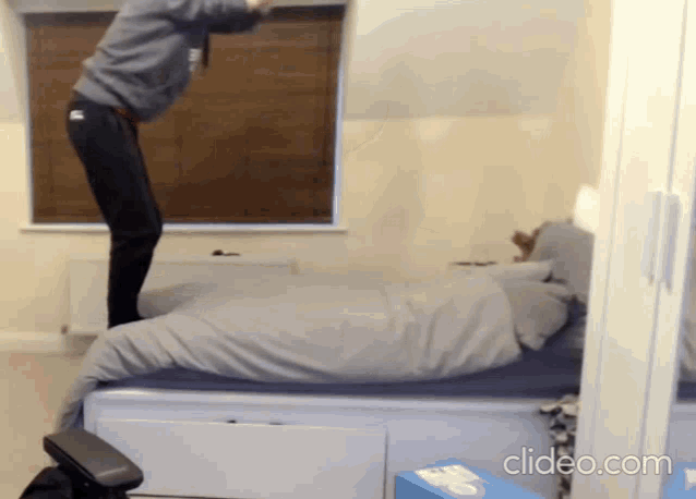 a person is jumping on a bed in a room with clideo.com on the bottom right
