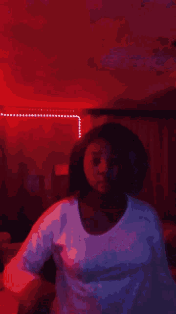 a girl is dancing in a room with red lights .