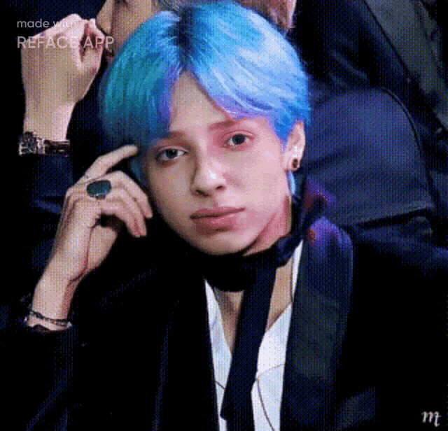 a man with blue hair is wearing a black jacket and tie