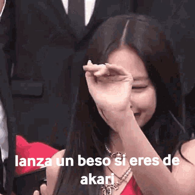 a woman is covering her face with her hand and the words lanza un beso si eres de akari are on the bottom