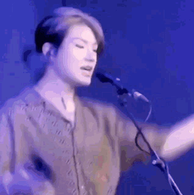 a woman is singing into a microphone while standing on a stage .
