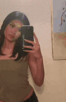 a woman is taking a selfie in a mirror with her phone .