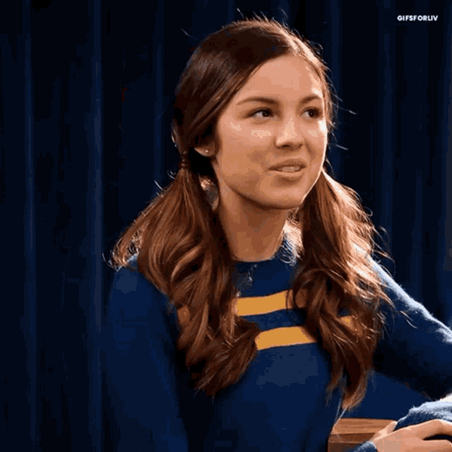 a girl with pigtails is wearing a blue and yellow sweater