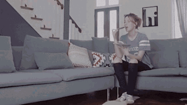 a woman sitting on a couch wearing a shirt that says ' aviator ' on it