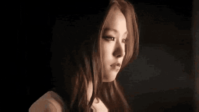 a close up of a woman 's face in a dark room looking at the camera .