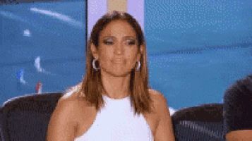 a woman in a white dress is sitting in a chair and making a funny face .