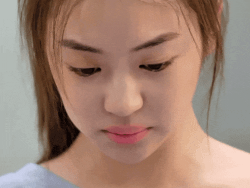 a close up of a woman 's face with a blue shirt