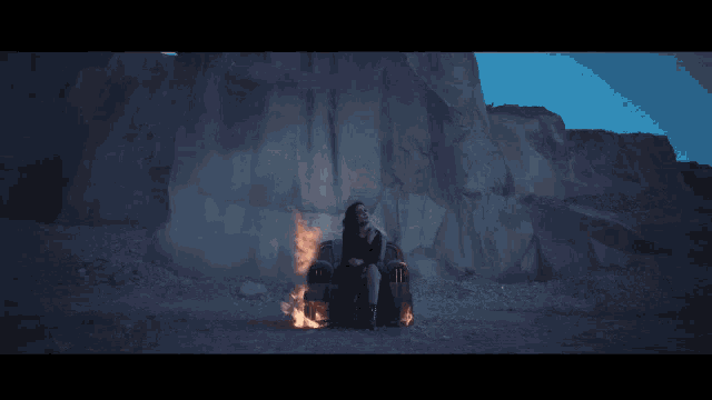 a woman sits in a chair in front of a mountain