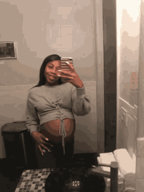 a pregnant woman taking a picture of herself in the mirror