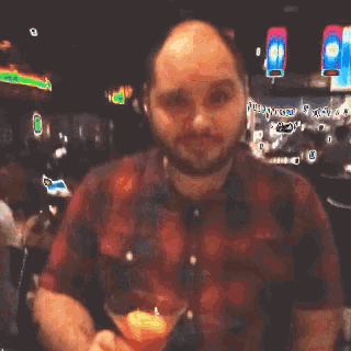 a man in a red plaid shirt is holding a glass