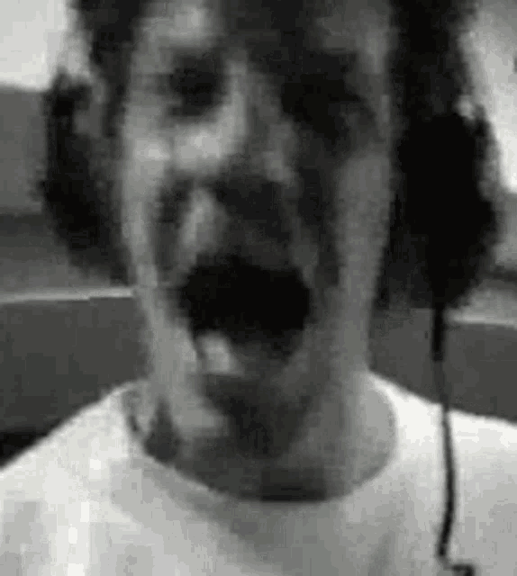 a man with a mustache is wearing headphones and screaming .