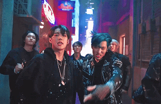a group of young men are standing in a dark alleyway with a neon sign that says pizza