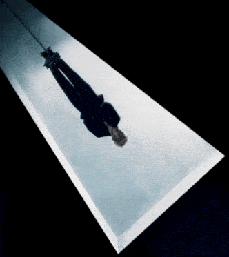 a person is hanging upside down from a rope in a dark room