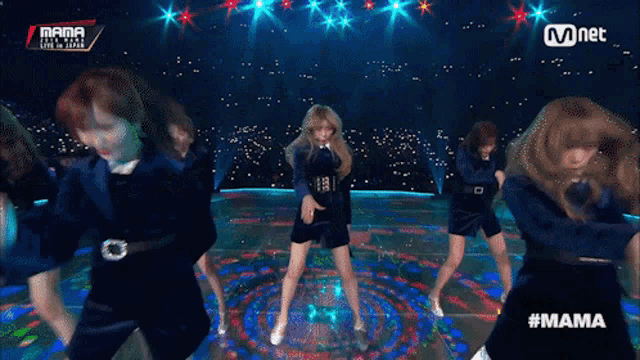 a group of women are dancing on a stage with mnet written on the bottom