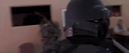 a man in a black helmet is standing in a room with a window .