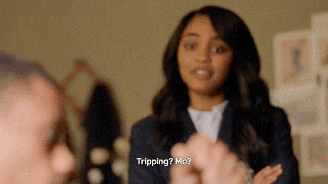 a woman in a suit is talking to a man in a room and says tripping me .