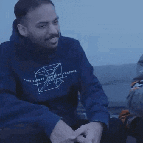 a man in a blue hoodie is sitting on a couch with a stuffed skeleton .