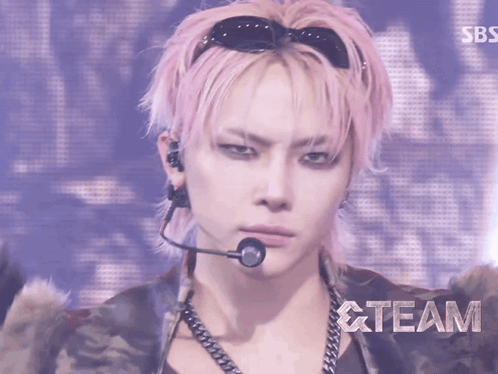 a man with pink hair is wearing sunglasses and a microphone and the word team is behind him
